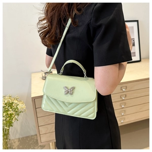 Detail of light green quilted crossbody bag with silver butterfly clasp and thin strap