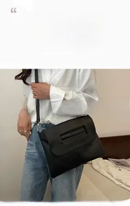 Detail of minimalist black PU leather crossbody bag with unique cutout handle design