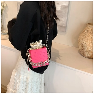 Detail of rose pink box bag with embossed lettering and chunky silver chain link