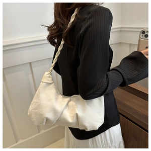 Détail d'un sac à bandoulière blanc plissé avec une bandoulière tressée sur un modèle