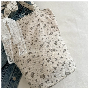 Detail of floral tote bag with bubble fabric texture and white lace bow decoration