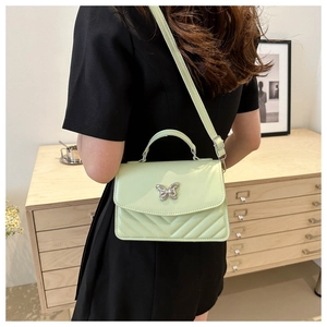 Close-up of mint green chevron quilted handbag with silver butterfly buckle and leather strap