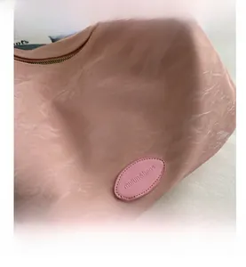 Gros plan d'un sac cabas rose montrant le cuir marbré et les détails du logo embossé