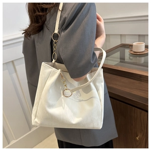 Dettaglio della borsa tote in pelle bianca con catena dorata e logo moda sulla spalla