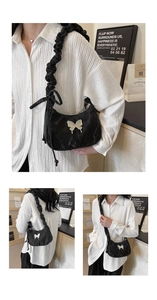 Detail of black pleated shoulder bag with silver butterfly and ruffled strap design