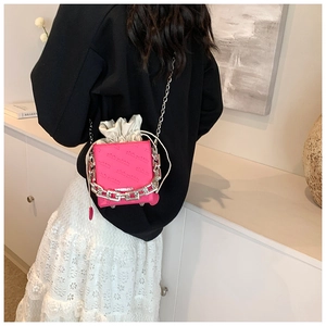 Detail of bright pink box bag featuring silver chain decor and drawstring closure