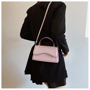 Close-up of pink glitter handbag with gold hardware shown on black blazer suit