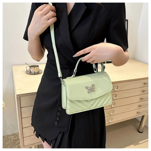 Close-up of mint green handbag with silver butterfly clasp and quilted pattern detail
