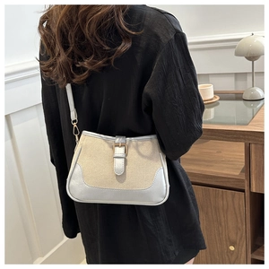 Lifestyle shot of a canvas crossbody bag with silver trim worn by a woman at home