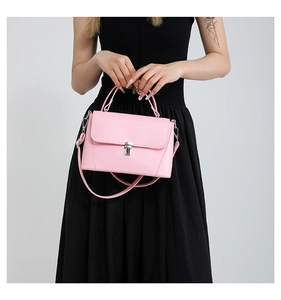 Detailed view of a pink leather crossbody bag with silver buckle worn by a model