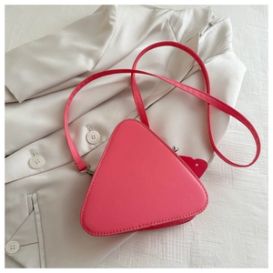 Dettaglio borsa a tracolla triangolare in pelle rosa con cuciture su blazer bianco