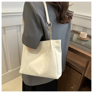 Dettaglio della borsa tote in PU bianco con etichetta 'FASHION' e tracolla a catena oro