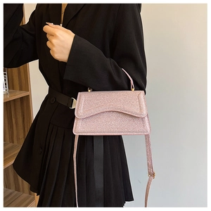 Detail of pink glossy textured crossbody bag with metal accents on a black suit model