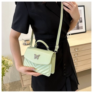 Detail of light green square bag with silver butterfly buckle and V-quilted texture