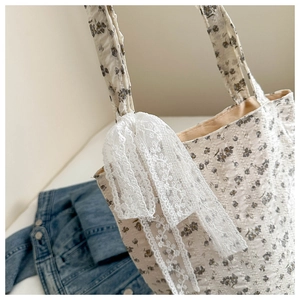 Detail of floral canvas tote bag with pleated texture and white lace bow decoration
