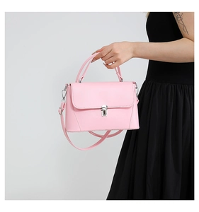 Pink leather shoulder bag with silver buckle worn by a model in a black dress