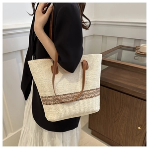 Detail of hand-woven straw tote with brown leather straps and openwork lace decoration