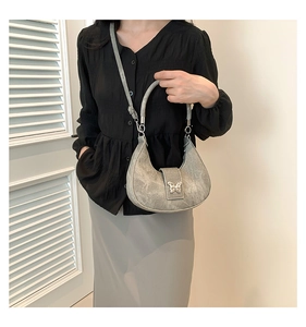 Détail du sac hobo croissant gris avec fermoir papillon en métal et texture raffinée