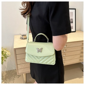 Detail of mint green quilted PU leather bag with silver butterfly clasp shown on model