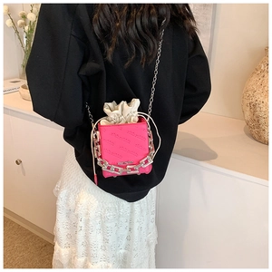 Detail of pink box bag with silver chain and white drawstring closure shown on a model