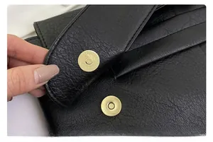 Close-up of black litchi grain leather bag featuring a high-quality metal magnetic clasp