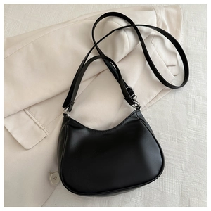 Detail of minimalist black semi-moon shoulder bag with smooth texture and silver hardware