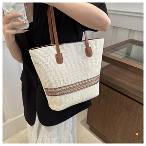 Detail of woven straw tote bag with brown lace trim and faux leather shoulder strap