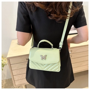 Detail of mint green crossbody bag with silver butterfly buckle and V-quilted pattern