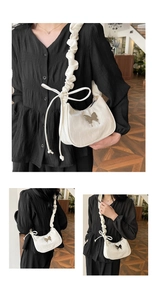 Detail of ruffled shoulder strap with silver butterfly charm on white shoulder bag