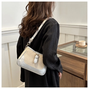Close-up of a beige canvas crossbody bag with metallic silver accents on a casual model