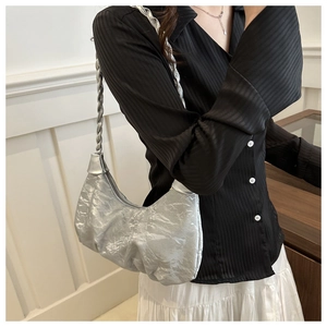 Détail d'un sac hobo argenté avec bandoulière tressée et texture de tissu froissé