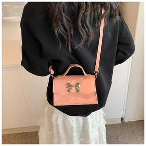 Pink orange crossbody bag with silver bow clasp worn by a model in a casual summer style