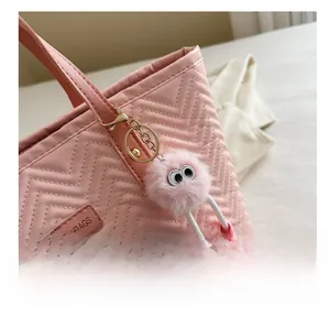 Dettaglio borsa shopper rosa trapuntata con ciondolo a mostro di peluche e logo fashion