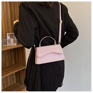 Chic pink glitter crossbody bag styled with a black blazer in a modern interior setting