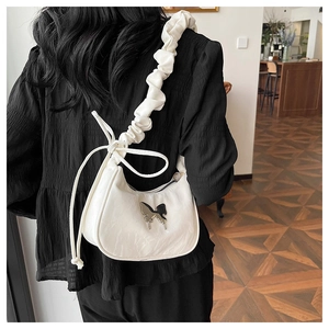 Detail of white crescent bag showing silver butterfly charm and ruched cloud shoulder strap