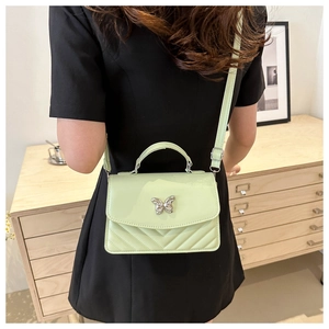Detail of mint green quilted bag with metal butterfly clasp and fine leather texture