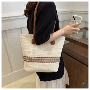 Detail of woven straw tote bag with brown lace trim and leather shoulder strap