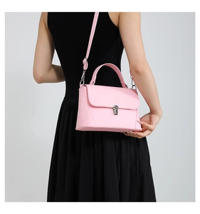 Model wearing a pink leather crossbody bag with a silver buckle over a black dress