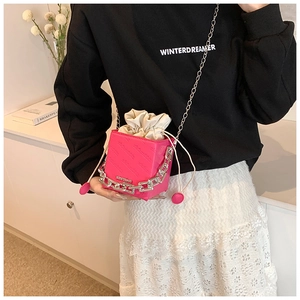 Detail of rose red drawstring bucket bag with silver chain and letter embossing