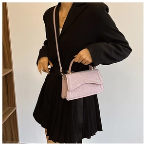 Chic pink glitter handbag shown on a model, featuring a top handle and shoulder strap