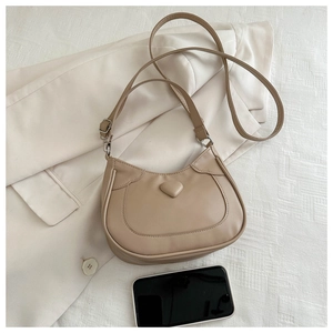 Close-up of beige PU leather shoulder bag featuring 3D heart decor and sleek stitching