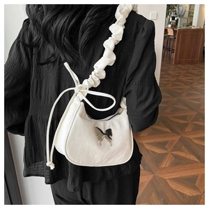Detail of white half-moon underarm bag with silver butterfly metal ornament and ruched strap