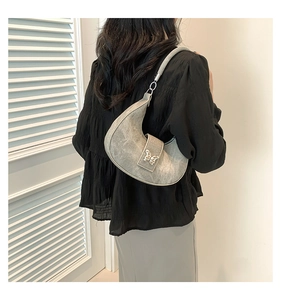 Vue détaillée du sac demi-lune gris avec papillon argenté porté par le modèle