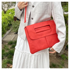 Détail d'un sac bandoulière en similicuir rouge vif avec des garnitures métalliques dorées