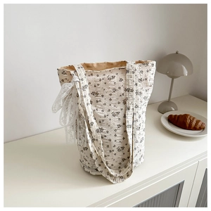 Detailed close-up of a floral canvas tote bag with a white lace bow and pleated texture