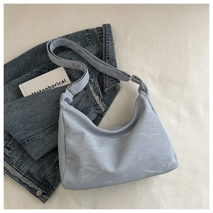 Détail d'un sac cabas plissé bleu clair avec bandoulière réglable sur tissu