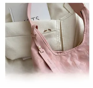 Vue détaillée du sac rose avec texture froissée brillante et pendentif en cuir