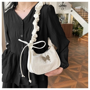 Detail of white scrunchie shoulder strap with a dainty bow on a crescent moon bag