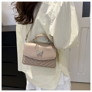 Model view of beige quilted handbag with silver butterfly clasp and slim shoulder strap