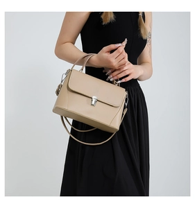 Detail of beige square handbag featuring silver metal twist lock and premium leather texture